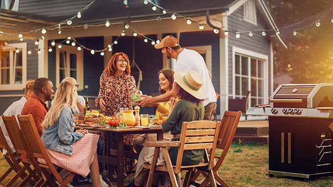 Sommeraktionsbild mit Menschen am Gartentisch bei sommerlicher Abendstimmung